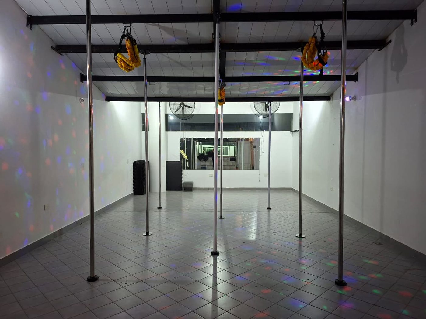 Sala del estudio con ocho caños montados, arneses de bungee colgando de las vigas, espejos y luces de colores.